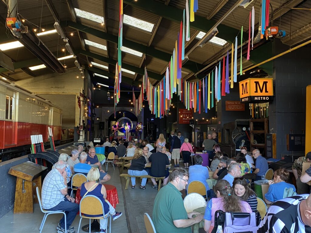 A view of our 2025 Ale By Rail event with people sitting in the museum drinking beer.